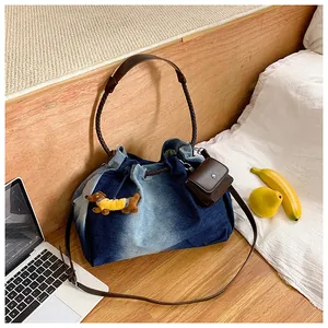 Detail of gradient denim tote bag with leather straps and plush dachshund charm