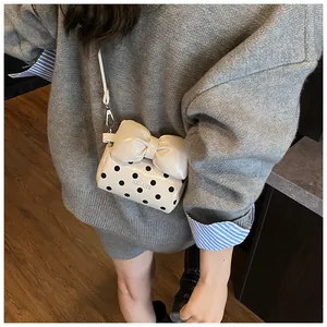 Close-up of mini polka dot crossbody bag featuring a large decorative bow and brand detail