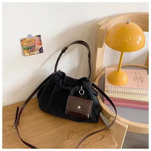 Detail of a drawstring bucket bag featuring a woven handle and a mini leather charm