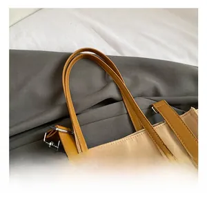 Detail showing high-quality leather handles and silver metal hardware on beige tote bag