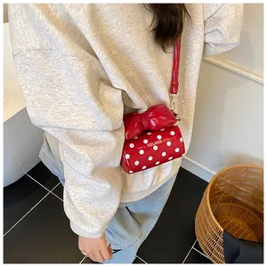 Close-up of red polka dot mini bag with oversized bow and brand logo on model
