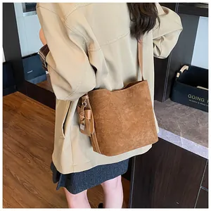 Detail view of brown matte bucket bag with mini pouch and silver hardware on shoulder