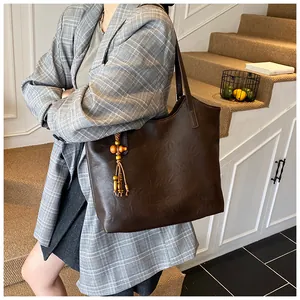 Detail of dark brown leather tote bag with vintage wood bead tassel on long strap