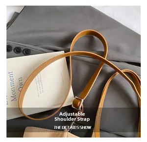 Detail of adjustable camel brown leather shoulder strap with silver buckle on tote bag