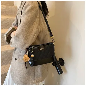 Detail showing the black quilted bucket bag texture with gold chain and cute bear charm