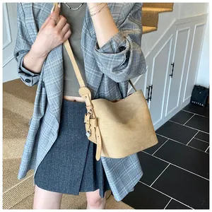 Detail of khaki suede bucket bag featuring side leather tassel and silver lock ornament