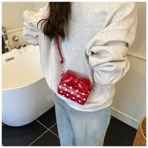 Detailed side view of a red polka dot mini bag featuring a large bow and thin shoulder strap