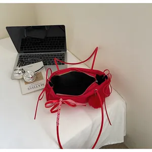 Draufsicht der roten Stofftasche mit Schleife, Plüsch-Anhänger und Laptop auf dem Tisch