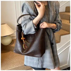 Detail of dark brown tote bag with wood bead tassel and subtle faux leather texture