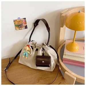 Detail view of cream canvas tote bag with woven handles and cute doll pendant on wooden table
