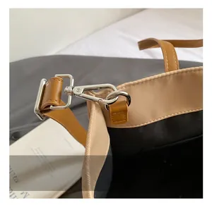 Detailed close-up of high-quality silver metal swivel hook and light brown leather bag strap