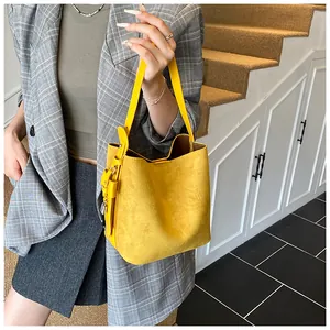 Detail view of bright yellow bucket bag with matte suede texture and metal lock charm