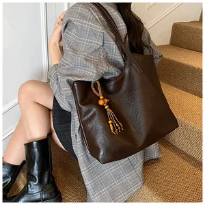 Detail of deep brown leather tote bag with vintage wood bead tassel and twin shoulder straps