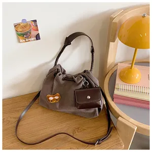 Detail of canvas bucket bag with cat patch, leather strap, and small hanging coin purse