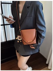 Borsa a secchiello in pelle marrone con placca dorata e un ciondolo a forma di leone