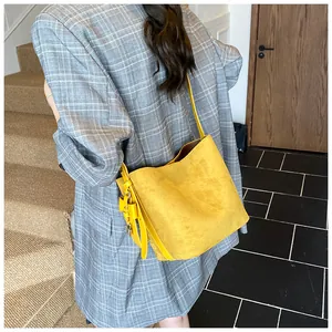 Detail view of bright yellow frosted bucket bag with leather strap and metal buckle accent