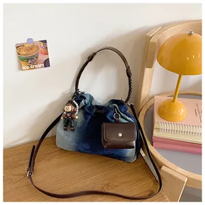 Detail of blue denim tote bag with woven brown handle and mini pouch in a lifestyle setting