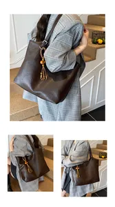 Detail of dark brown tote bag with leather texture and a decorative beaded tassel charm