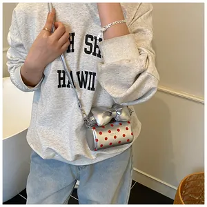 Detailed shot of silver mini crossbody bag with red polka dots and bow accent on a model