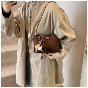 Detail view of brown quilted bucket bag with golden chain and baseball theme keychain