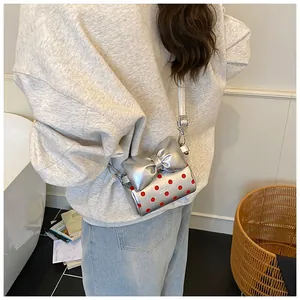 Detail of silver mini crossbody bag with red polka dots and a large bow decoration