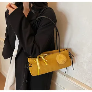 Seitenansicht der senfgelben Wildleder-Schultertasche mit Schleife und Bommel-Anhänger