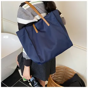 Detail of navy blue large capacity tote bag with contrasting brown shoulder straps