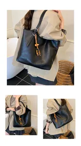 Detail of black PU leather tote bag with wooden bead and tassel charms on strap