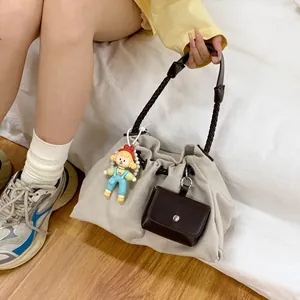 Large beige canvas tote bag with woven shoulder strap and cute doll pendant