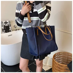 Detail of navy blue large tote bag with brown leather handles and adjustable shoulder strap