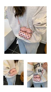 Detail of pink polka dot mini bag featuring a large bow and glossy leather texture