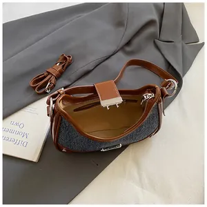 Detail of blue denim and brown leather patchwork bag with silver buckle and inner zipper