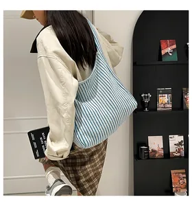 Detail showing blue and white striped knitted tote bag on model for casual daily use