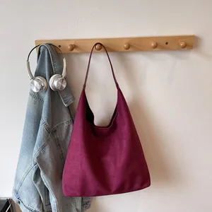 Detail of burgundy matte faux suede hobo tote bag hanging with stylish accessories
