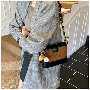 Chic quilted bucket bag with gold chain strap and baseball charm shown on model