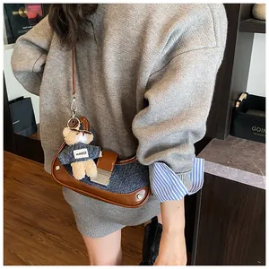 Detail of retro denim and brown leather underarm bag with cute bear charm and silver clasp