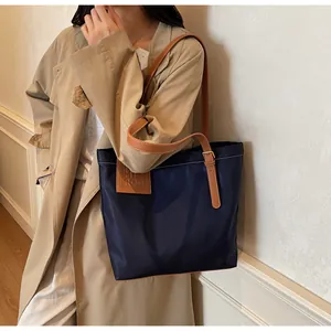 Detail van marineblauwe nylon shopper met leren riemen en reliëf MIROO-logo