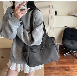 Détail du sac cabas en nylon gris foncé montrant la poche latérale et l'écusson logo