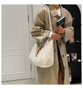 Detailed view of large striped canvas tote bag with beads on a model in beige coat