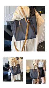 Detail view of large black tote bag featuring camel leather straps and side pocket detail