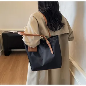 Detailopname van de zwarte nylon shopper met bruine lederen handvatten en merklabel