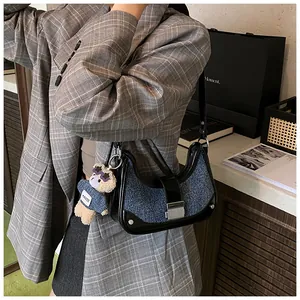 Detail view of vintage denim shoulder bag with leather trim and plush bear charm