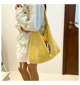 Detail of striped canvas tote bag with multi-color wooden bead charm and soft texture