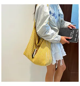 Detail of striped canvas tote bag with colorful bead charm on a casual outfit