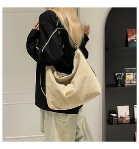 Dettaglio della borsa hobo in tela beige chiaro con etichetta in pelle e trama del tessuto