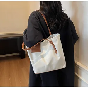 Detailopname van beige shopper met bruine leren riem en logo in reliëf