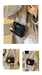 Detail of black quilted bucket bag with gold logo plate and baseball charms