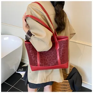 Detail of dark red leopard print pattern on a high-capacity tote bag worn by a model