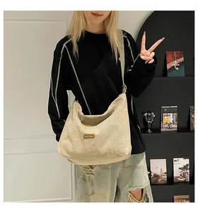 Dettaglio della borsa tote in tela crema con etichetta in pelle marrone e stile hobo