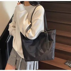 Detail van zwarte shopper met witte contraststiksels en verstelbare gesp aan de riem